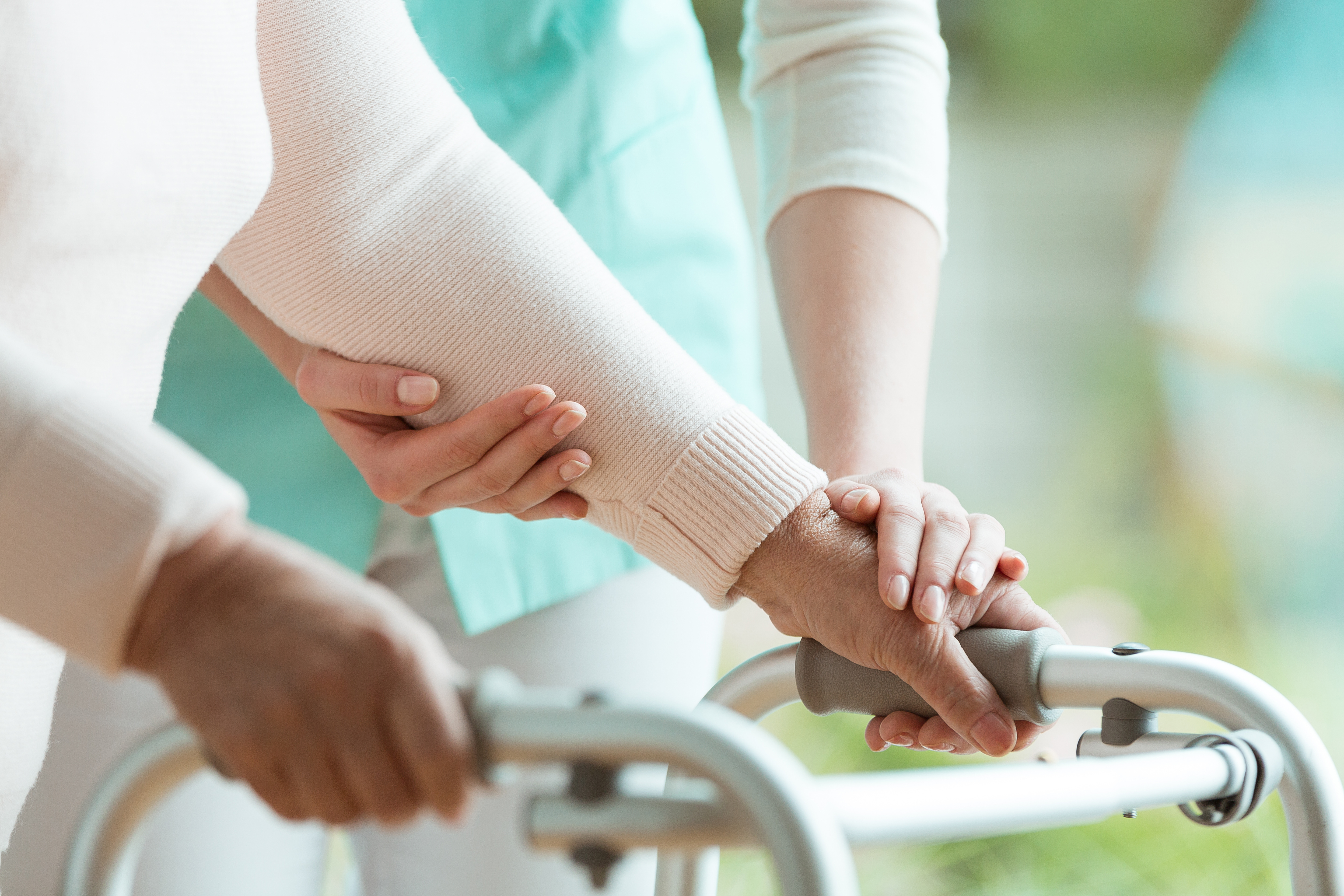 Closeup of senior lady's hands holding a walker and helpful nurs