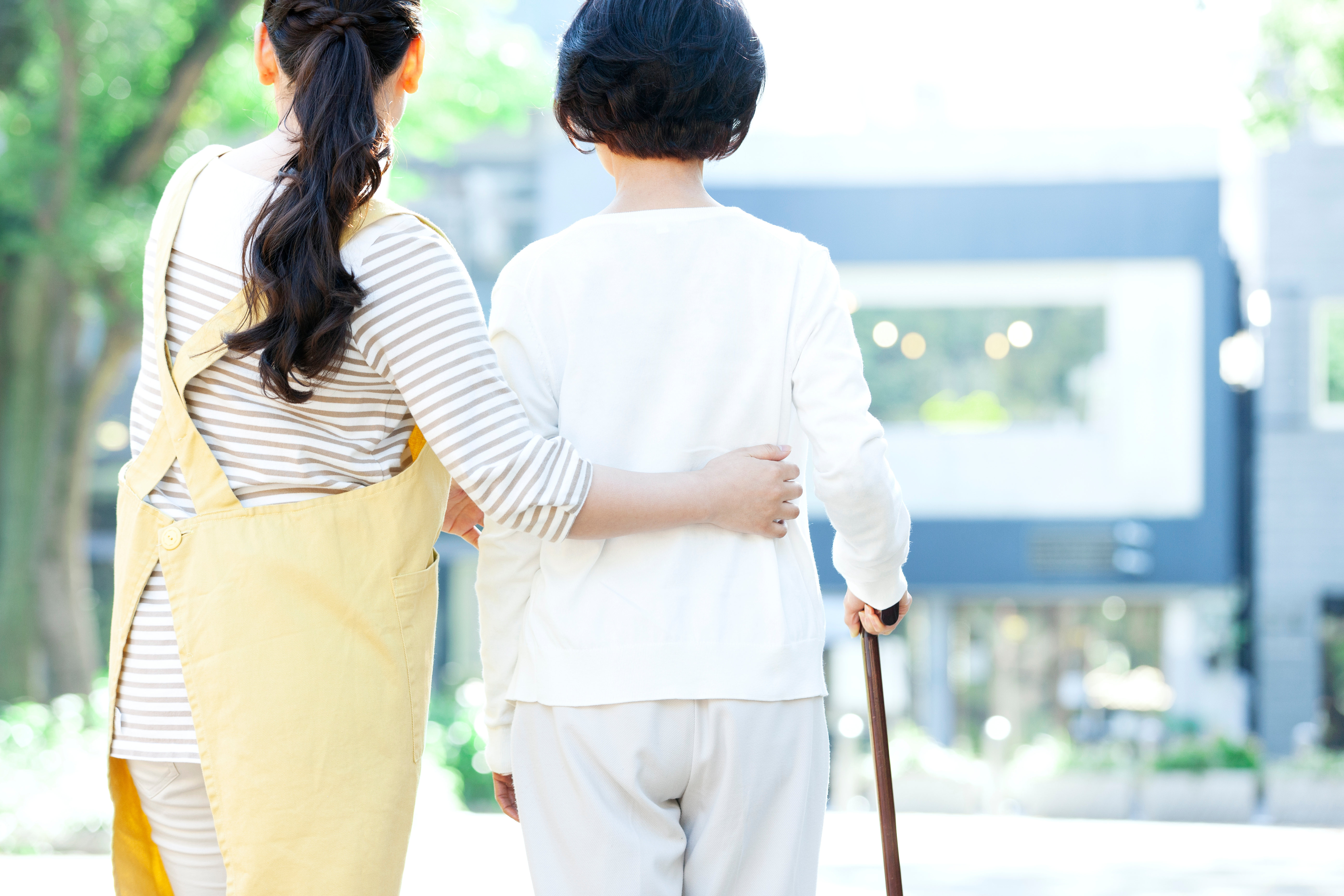 シニア女性の歩行を介助する女性介護士の後ろ